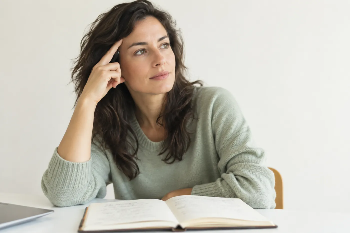 Woman thinking quietly beside an open journal