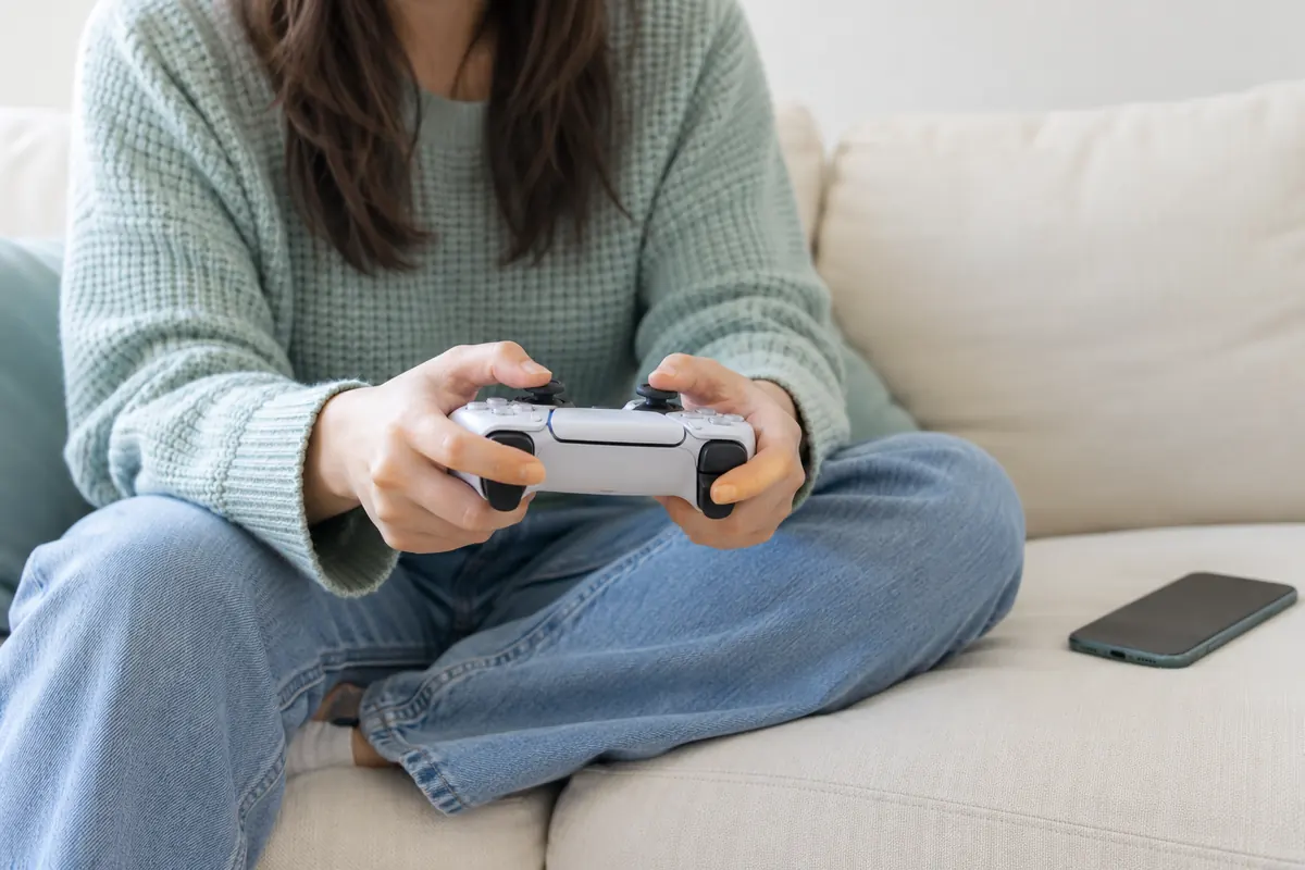 Hands holding a video game controller while relaxing on a comfortable sofa